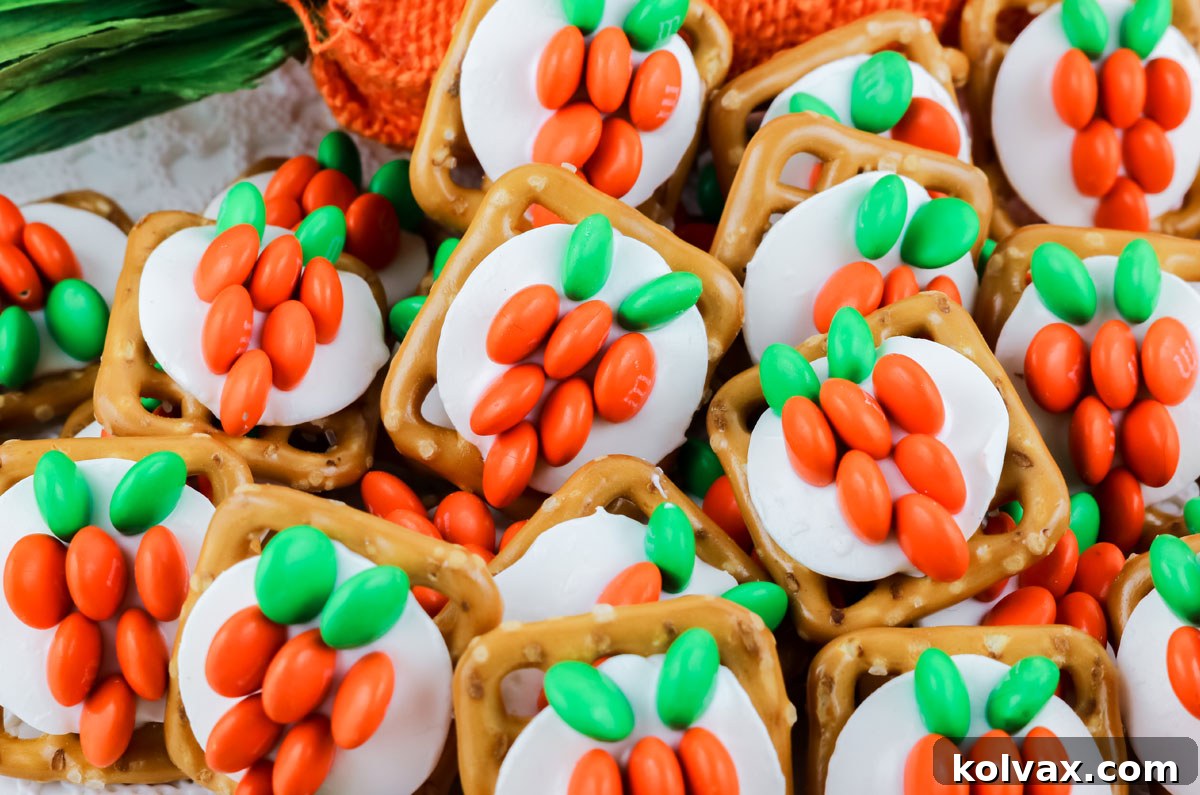 A close-up view of a vibrant pile of Easter Bunny Carrot Pretzel Bites resting on a pristine white surface, highlighting their bright orange and green colors.