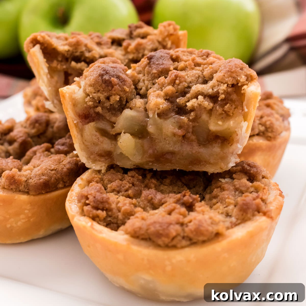 Closeup on a Mini Apple Pie that has been cut in half to show the filling and the crumb topping, revealing its delicious layers.