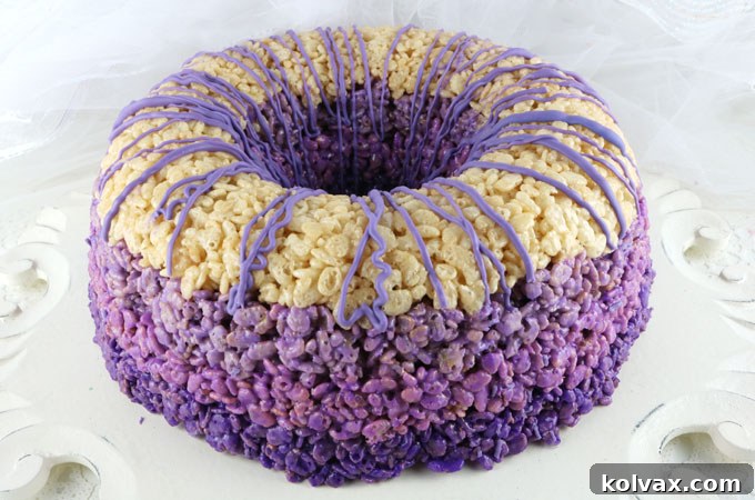 Ombre Rice Krispie Cake - A stunning, delicious, and effortlessly unique dessert. This beautiful purple ombre creation is guaranteed to impress family and party guests alike. Loved by all ages, Rice Krispie Treats are transformed into an elegant, easy-to-make cake that will become your go-to recipe. Pin for later and follow us for more amazing Rice Krispie Treat ideas and recipes.
