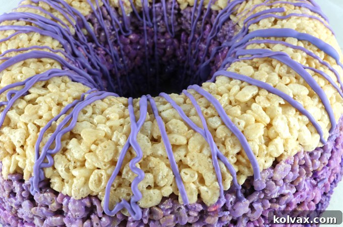 Drizzle the melted candy melts onto the top of the cake - The artistic step of applying the freshly melted purple candy melt mixture over the top surface of the Ombre Rice Krispie Cake, creating an elegant, decorative finish.