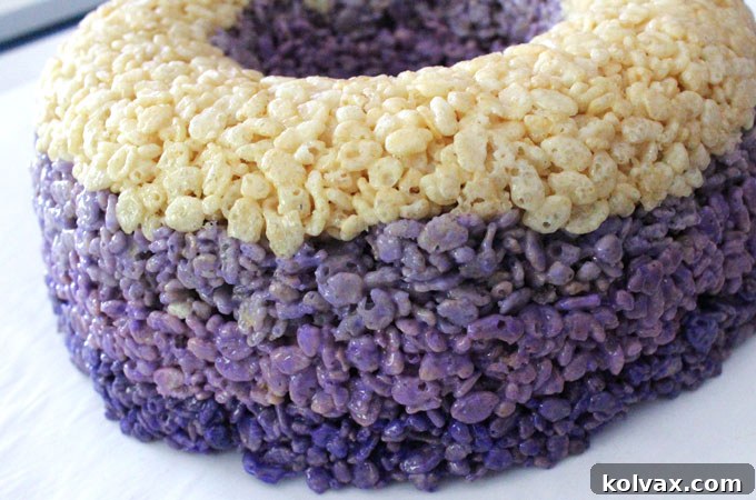 Continue adding all of the color Rice Krispie Treat mixture layers - The final stages of assembling the Ombre Rice Krispie Cake, with all four distinct, colorful layers firmly pressed into the bundt pan, ready for the chilling and final adornment.