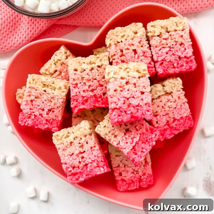 A batch of Ombre Rice Krispie Treats in a heart shaped bowl laying on a white table.