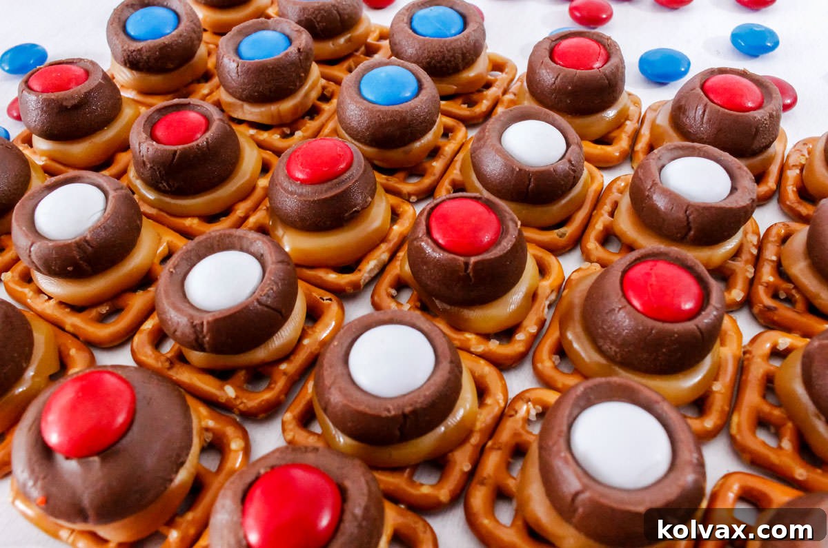 Close-up of a group of vibrant Patriotic Caramel Pretzel Bites arranged on a white surface, surrounded by scattered red, white, and blue M&M's, highlighting their festive appeal.