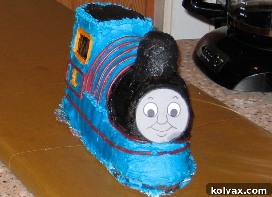 Detailed view of Thomas the Train cake face, achieved with a laminated printed image for perfect recognition, set against blue frosting.