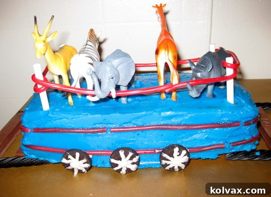Close-up of the animal car for the Thomas the Train cake, featuring miniature farm animals behind red licorice fences supported by lollipop sticks.