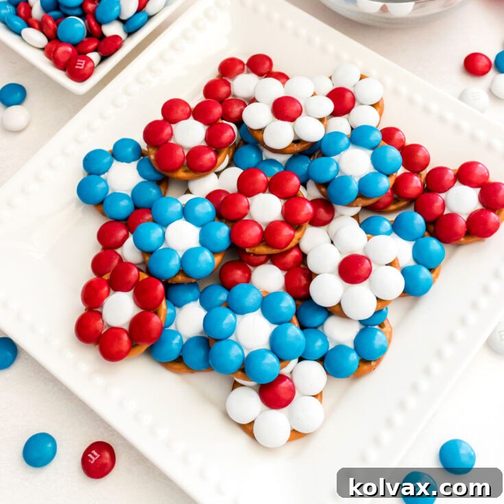 Closeup on a white dessert dish filled with Patriotic Flower Pretzel Bites sitting on a white table.