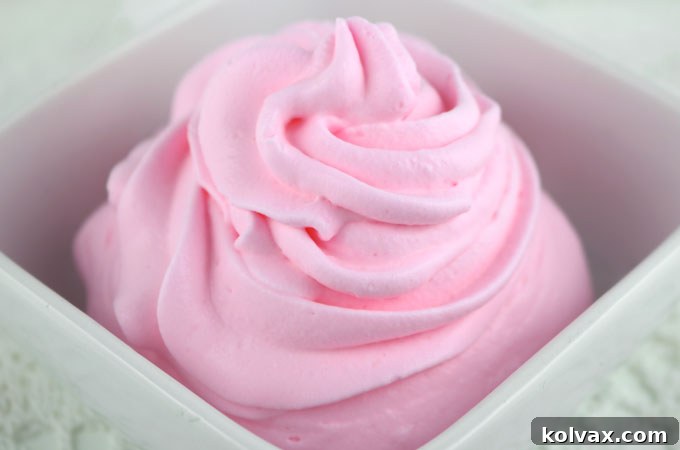 Vibrant pink homemade colored whipped cream swirled on a dessert, highlighting its beautiful hue and creamy texture.