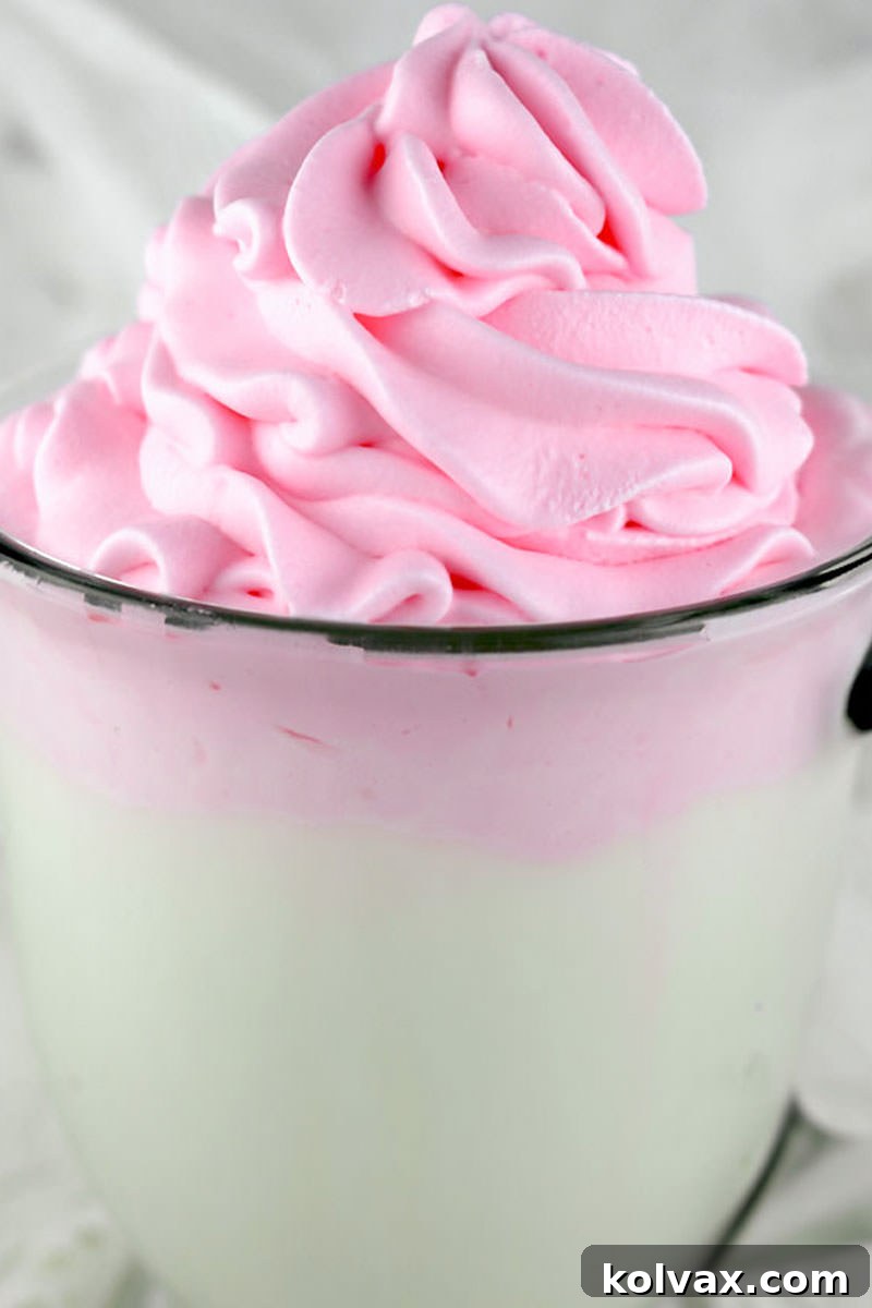A vibrant pink colored whipped cream dessert, garnished with sprinkles, inviting a delightful treat.