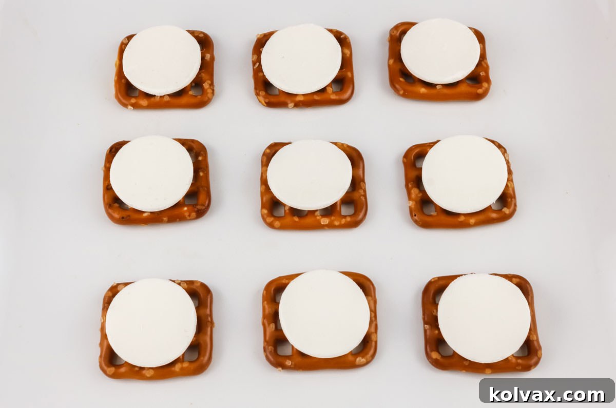 Pretzel Blossom Bites 4 Nine pretzels sitting on a white surface topped with a single White Chocolate Melting Wafer.