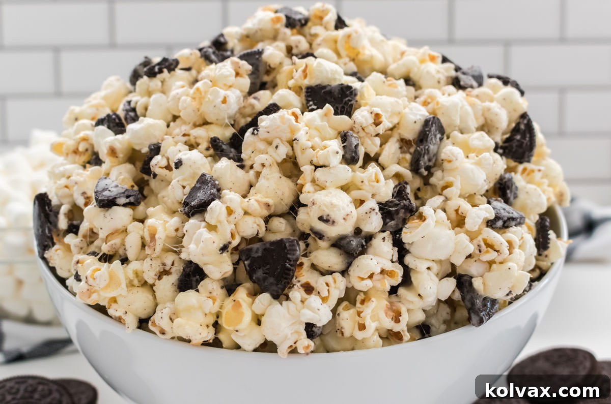 Midnight Cookie Pop 2 Close-up of a white serving bowl brimming with homemade Oreo Popcorn, set on a pristine white table and surrounded by whole Oreo Cookies, inviting a delightful indulgence.
