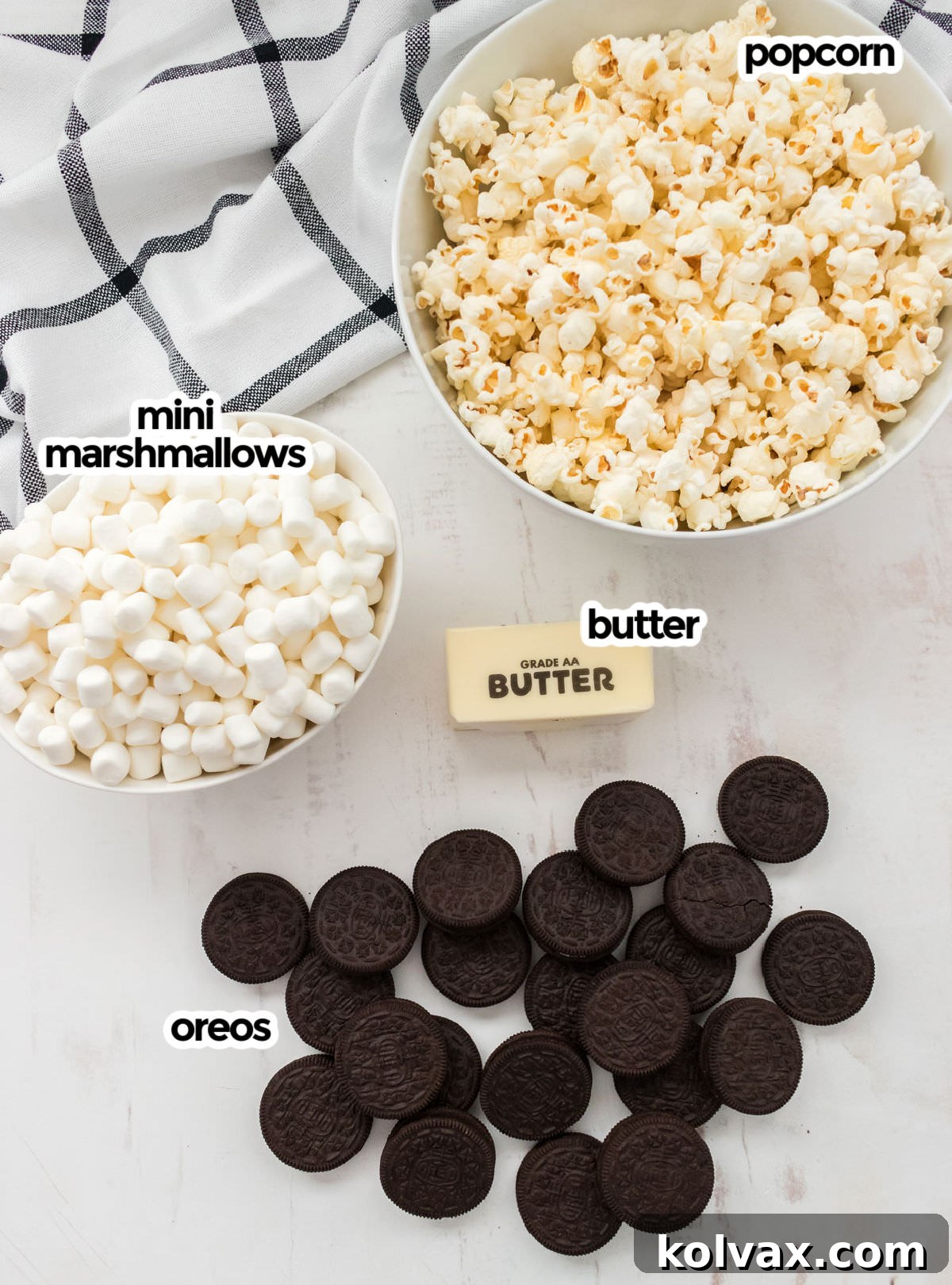 Midnight Cookie Pop 3 A vibrant flat lay showcasing all the essential ingredients needed for homemade Oreo Popcorn: golden popped popcorn, a bowl of fluffy mini marshmallows, a stick of butter, and a stack of classic Oreo Cookies.