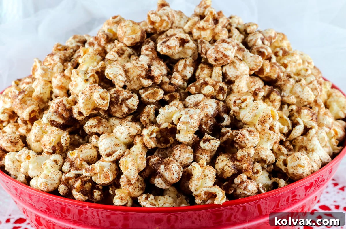 Closeup of a vibrant red bowl brimming with Cinnamon Toast Popcorn, resting on a lace-covered red table, showcasing the golden kernels coated in cinnamon sugar.
