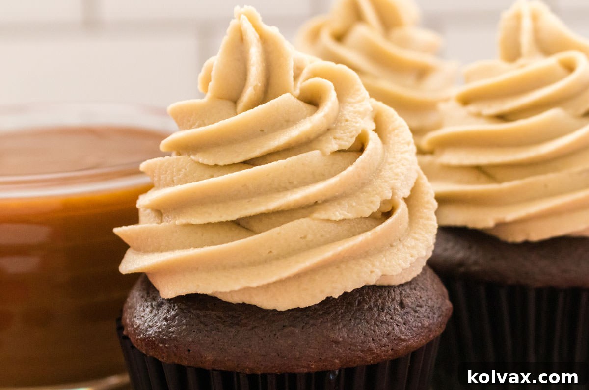 Closeup on three chocolate cupcakes frosted with a swirl of The Best Caramel Buttercream Frosting, showcasing its rich texture and appetizing appeal.