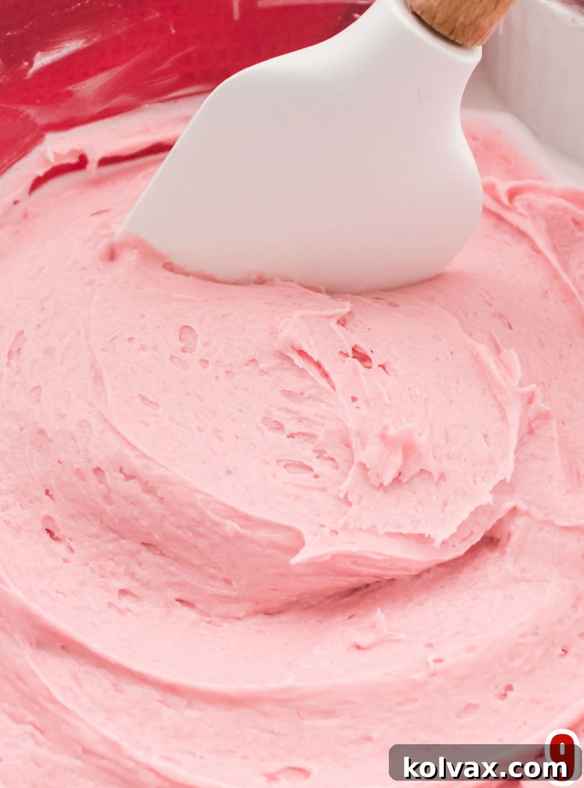 Rich, vibrant homemade Raspberry Buttercream Frosting in a clear glass bowl, showcasing its smooth and fluffy texture.
