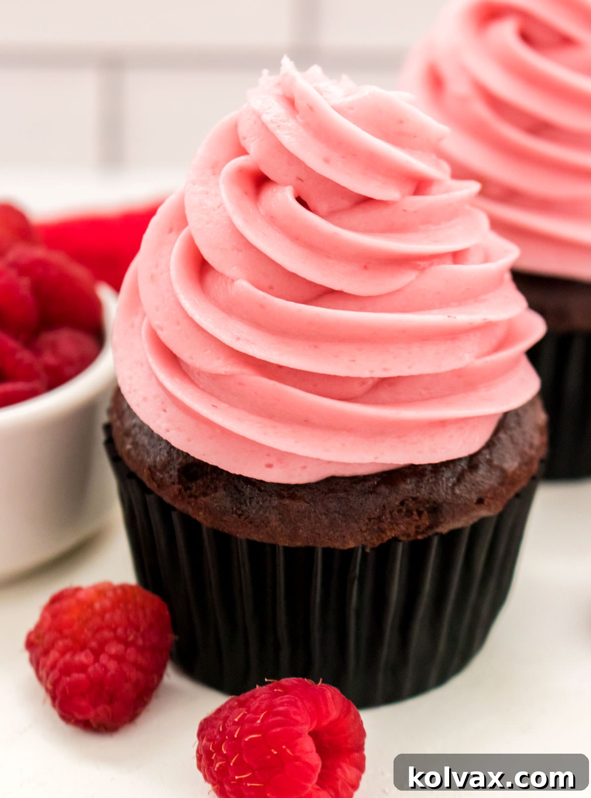 A beautifully frosted cupcake featuring homemade Raspberry Buttercream Frosting, garnished with fresh raspberries for a vibrant and delicious finish.