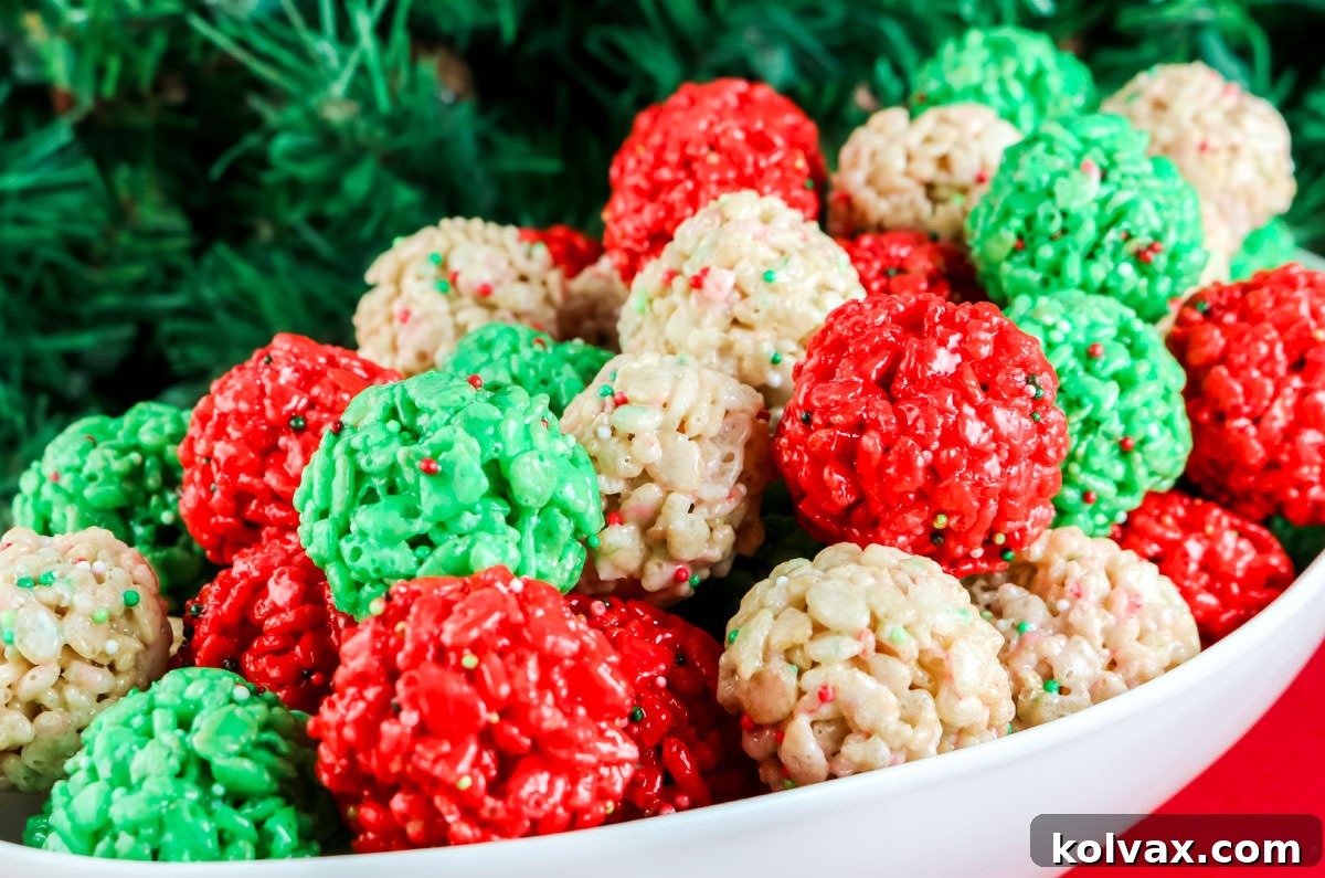 A beautiful white serving bowl brimming with festive red, green, and white Christmas Rice Krispie Treat Bites, set against a cheerful red background adorned with subtle Christmas greenery, creating a vibrant holiday scene.