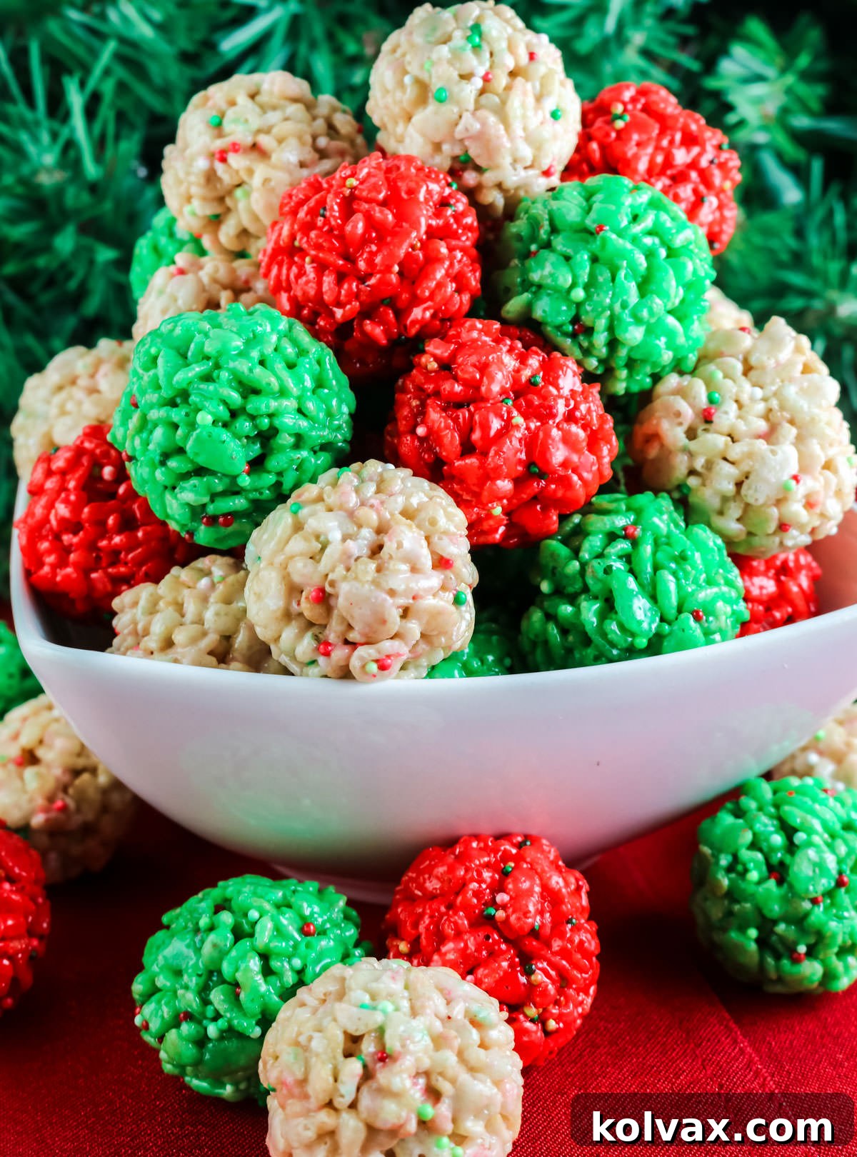 A close-up of a rustic white bowl overflowing with a delightful mix of red, white, and green Christmas Rice Krispie Treat Bites, emphasizing their vibrant colors and perfect round shapes, ready for serving.