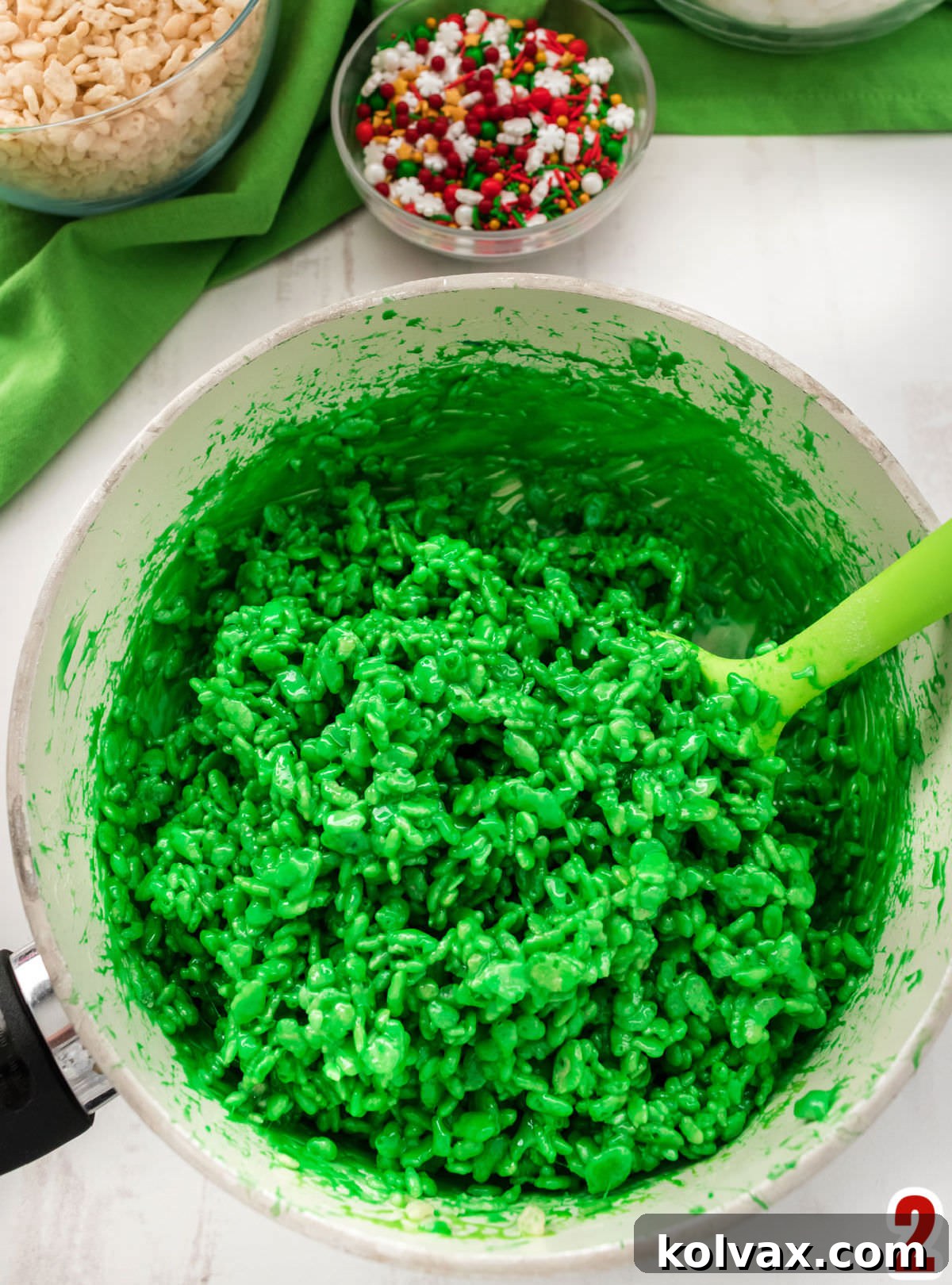 An overhead shot of a white pan filled with a uniformly green Rice Krispie Treat mixture, ready for shaping.