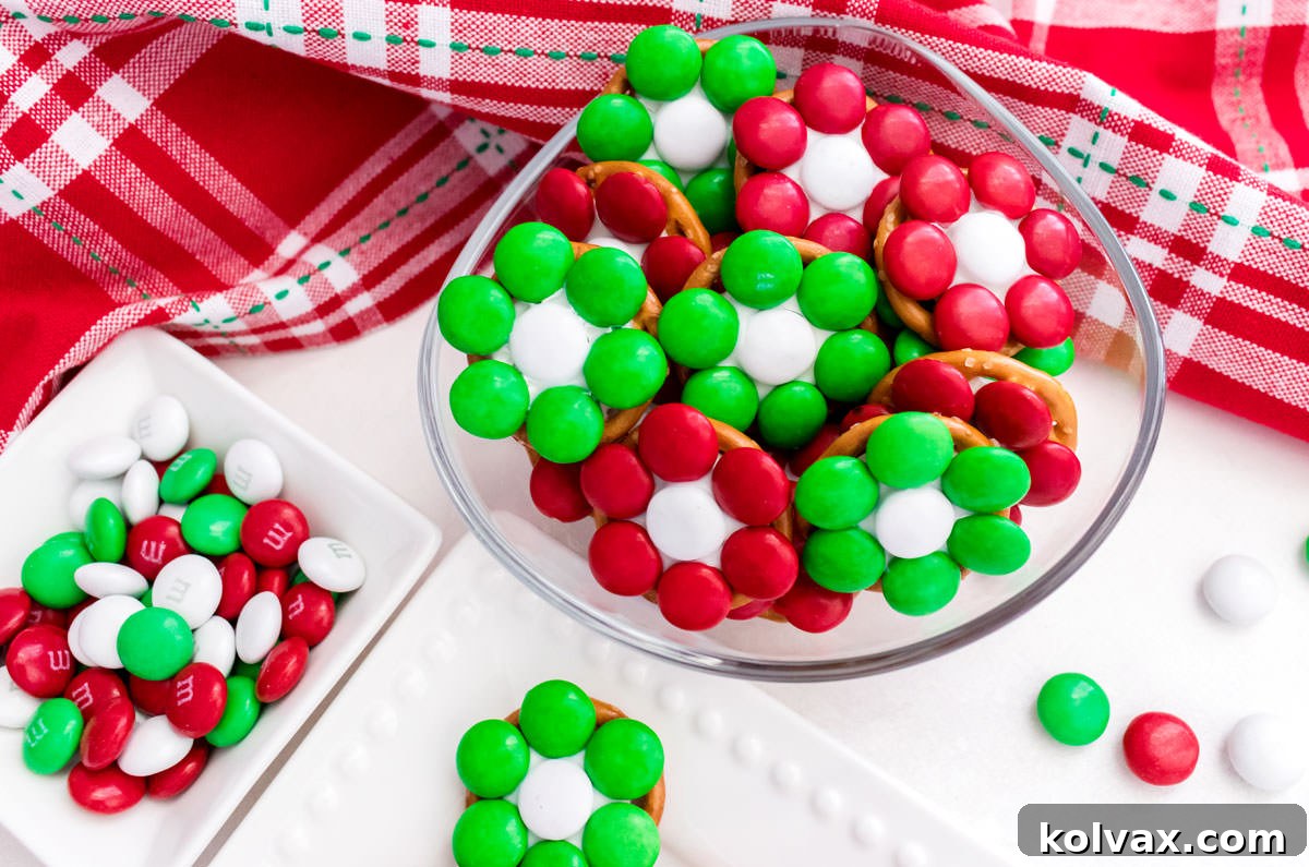 Closeup on a small glass bowl filled with Christmas Flower Pretzel Bites sitting next to a ramekin filled with Red, White and Green M&M's.