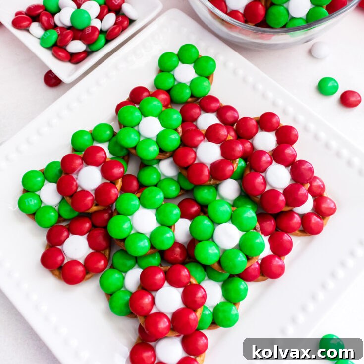 Closeup on a batch of Christmas Flower Pretzel Bites sitting on a white dessert plate on a white table.