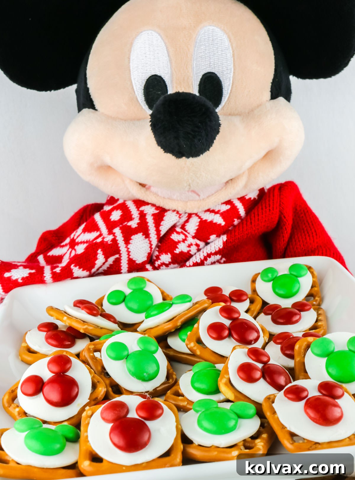 Festive Mickey Pretzel Delights 5 Closeup on a Mickey Mouse Stuffed Animal holding a white plate filled with Christmas Mickey Mouse Pretzel Bites, emphasizing their Disney charm.