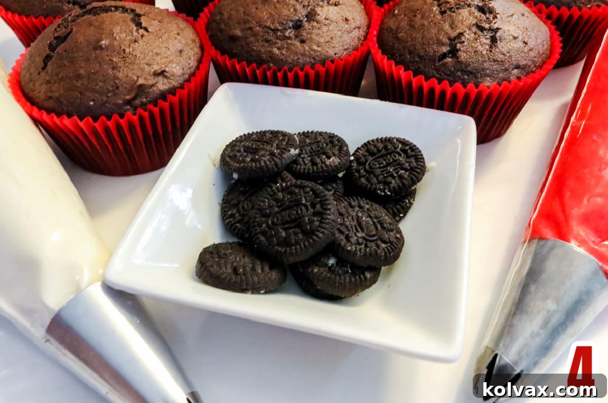 Mickey's Jolly Santa Hat Cupcakes 6 White ramekin filled with Mini Oreos surrounded by decorating bags filled with red and white frosting, and baked chocolate cupcakes.