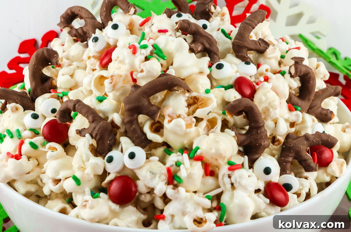 Close-up of a white bowl overflowing with festive Reindeer Popcorn, featuring candy reindeer faces and Christmas sprinkles.