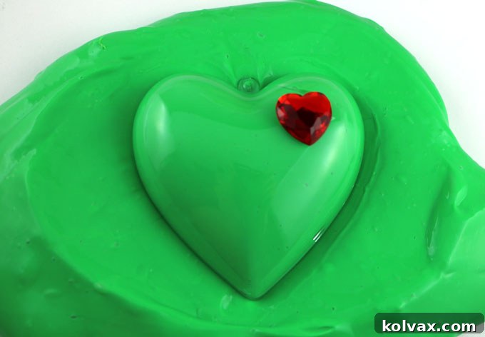 Our Grinch Slime - fun and colorful homemade GAK that would be great as a Christmas Stocking Stuffer or a Holiday Party Favor. We have step by step directions on how to make this easy to make DIY Christmas Craft. The kids will love playing with this ooey, gooey Holiday sensory activity. Follow us for more fun Christmas DIY Gifts.