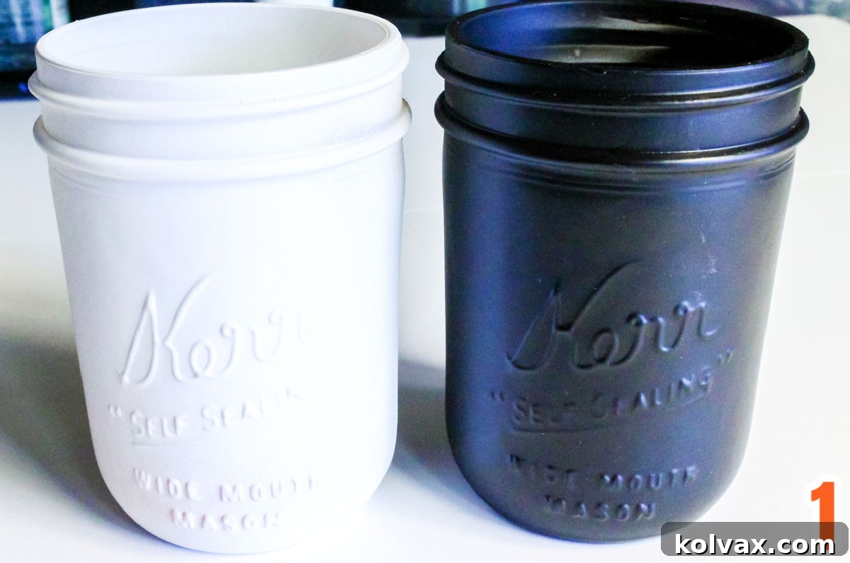 Two clean pint-sized Mason Jars, one expertly painted in crisp white and the other in sleek black, ready for further decoration.