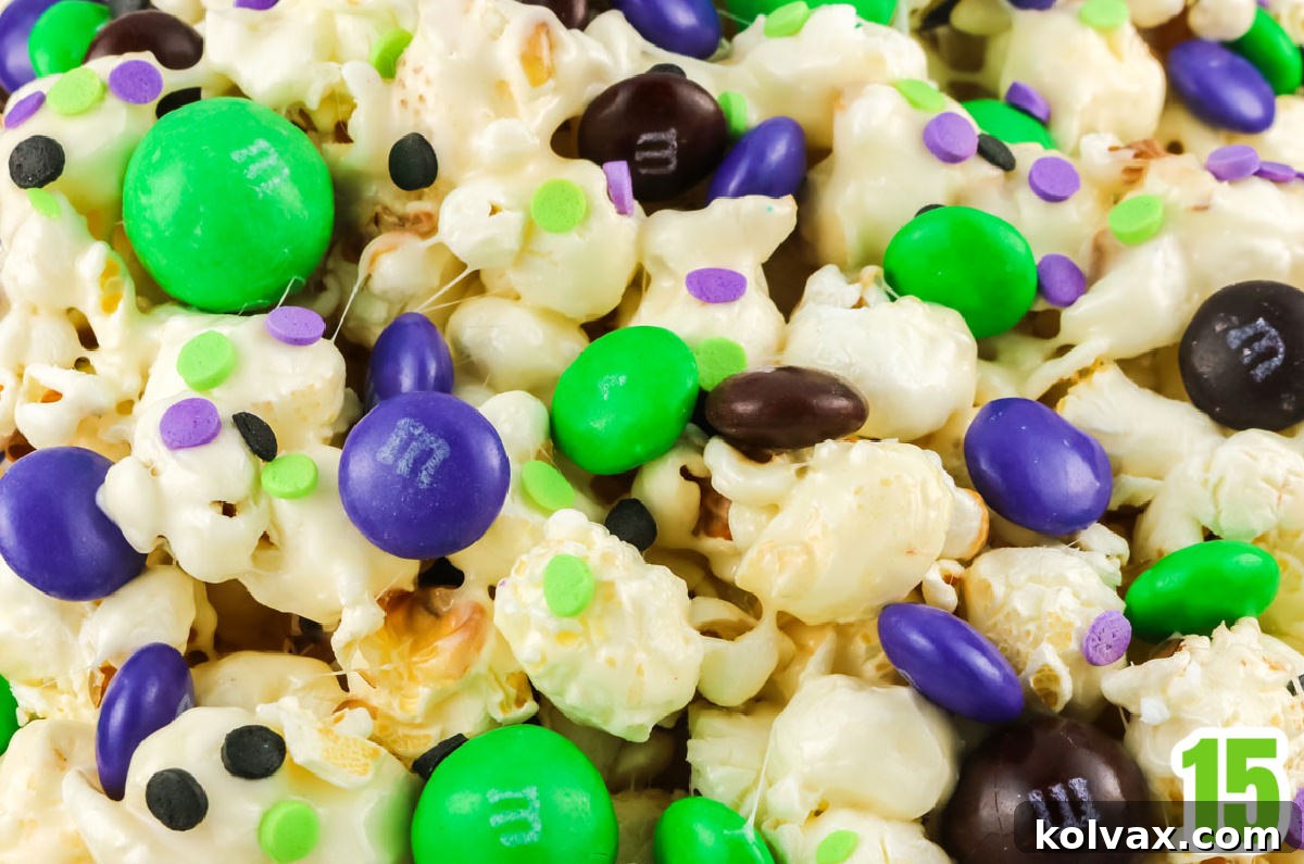 Closeup of a batch of Bewitched Halloween Popcorn showing the marshmallow popcorn sprinkled with Halloween colored M&M's and sprinkles.