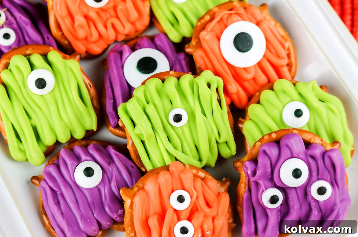 A vibrant platter overflowing with colorful Monster Pretzel Bites, featuring green, orange, and purple candy melts and various googly eye arrangements, perfect for Halloween celebrations.