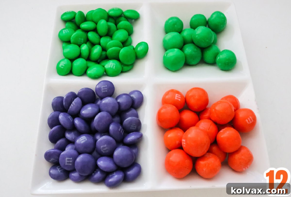 Closeup on a white ramekin filled with green, orange and purple M&M's.