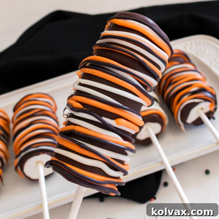 Wicked Marshmallow Wands 9 Closeup on a Halloween Marshmallow Pop hovering over a white table with a black kitchen towel.