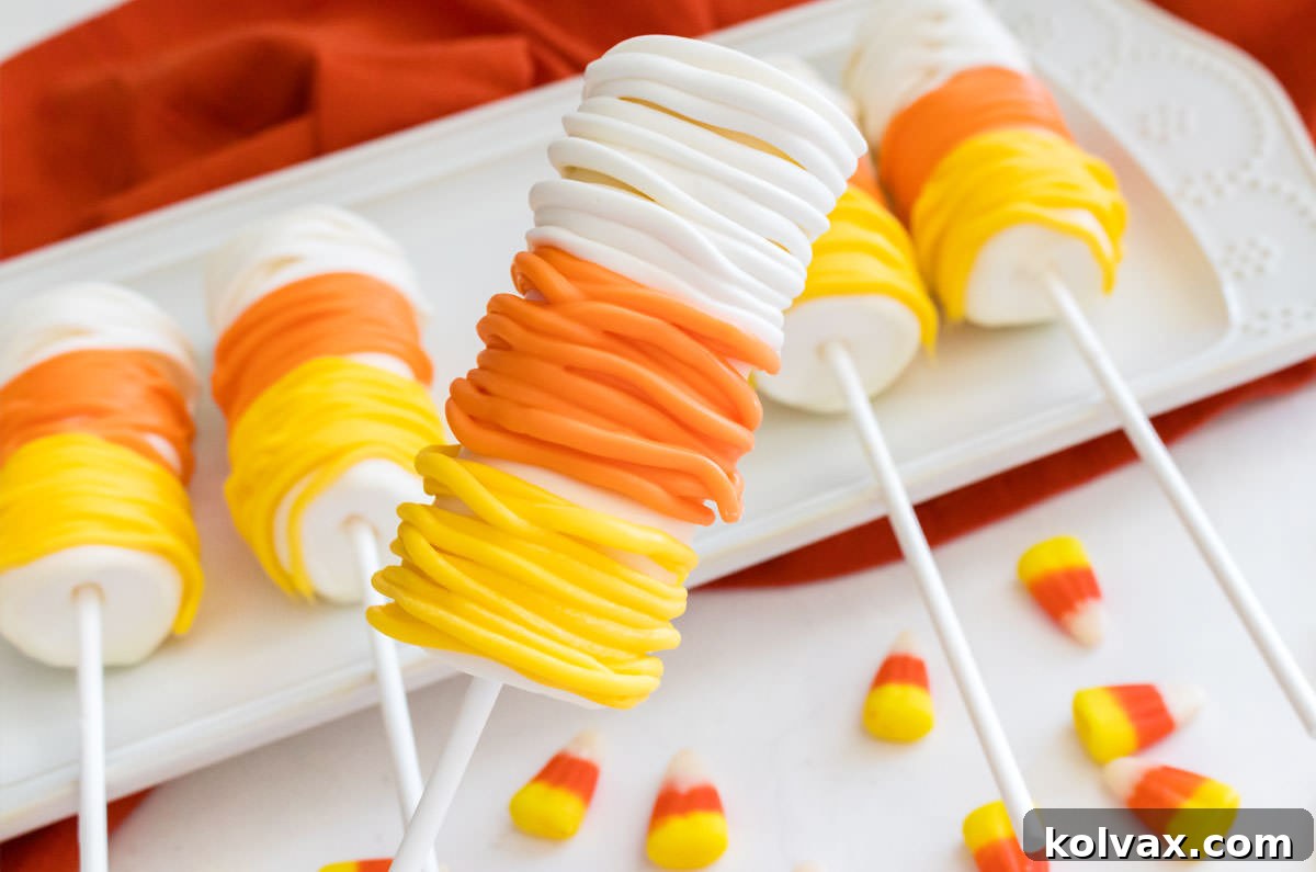 A closeup of a vibrant Candy Corn Marshmallow Pop, perfectly crafted with white, orange, and yellow candy melt layers, hovering gracefully over a pristine white plate, which rests on a cozy orange kitchen towel. This image perfectly showcases the dessert's festive appeal and deliciousness, making it an ideal choice for Halloween party treats.