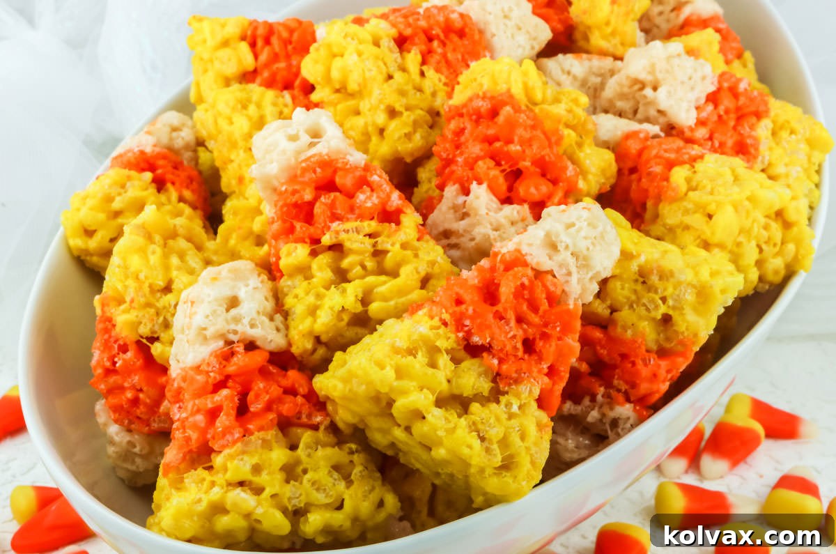 Candy Corn Crunch Bars 2 Closeup on a white oval serving bowl filled with Candy Corn Rice Krispie Treats.
