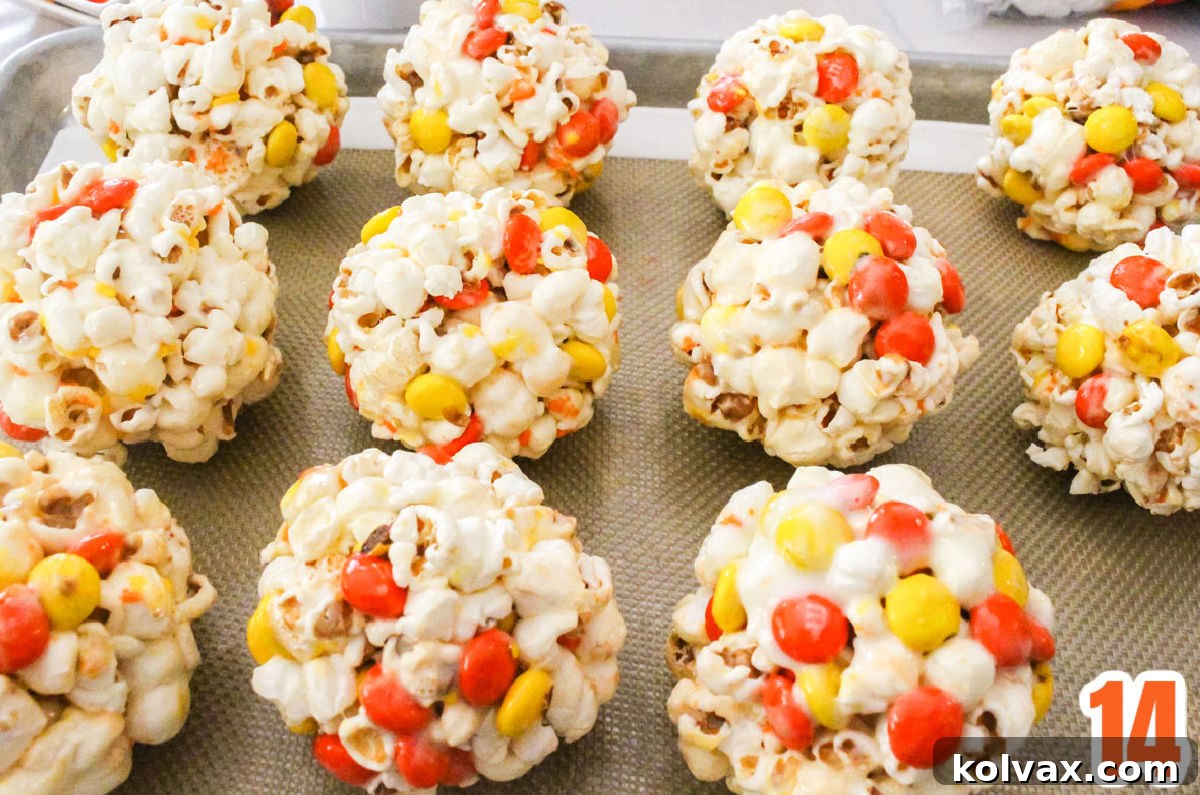 A dozen Halloween Popcorn balls sitting on a baking sheet, freshly made.