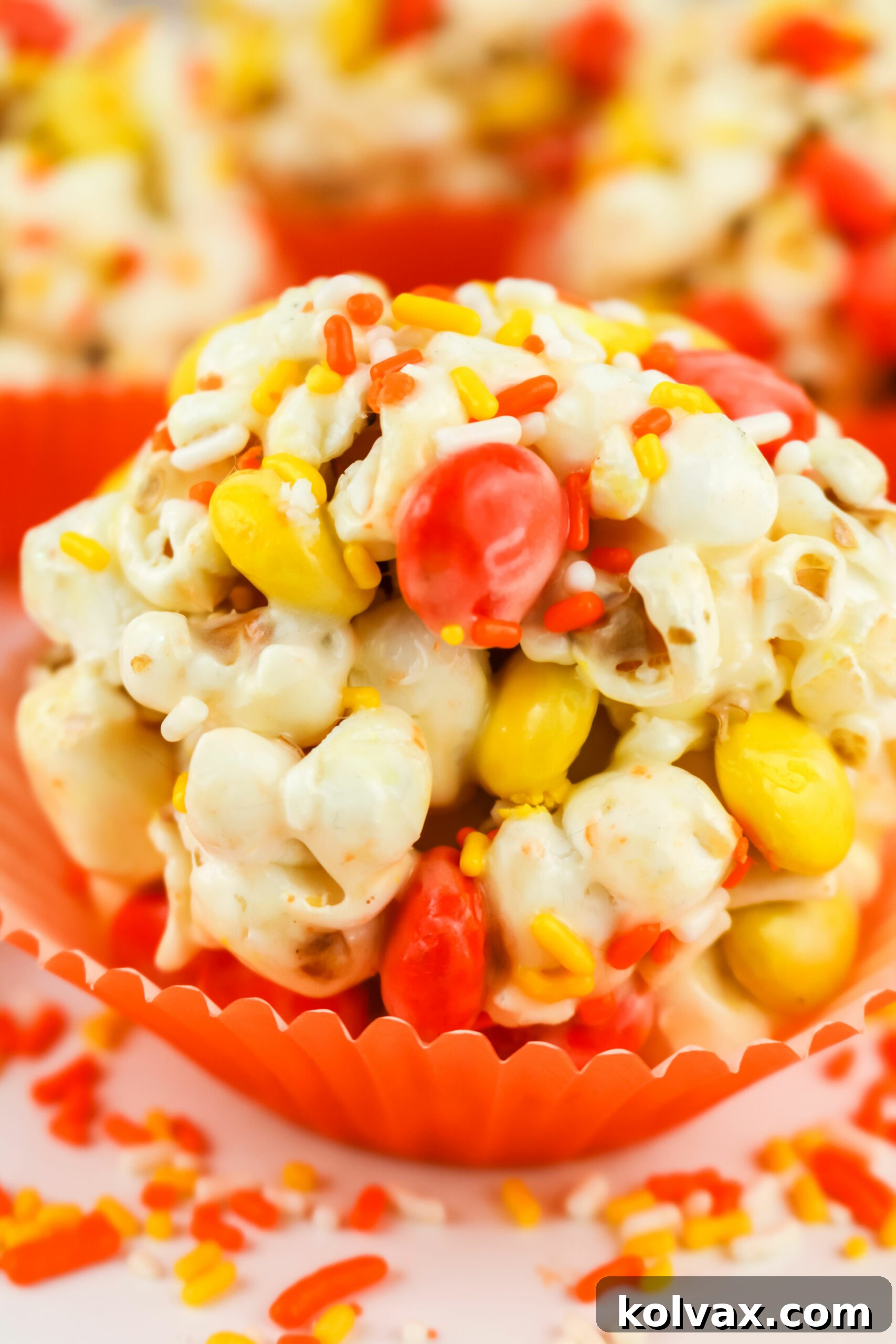 Closeup on a single Halloween Popcorn Ball sitting in an orange cupcake liner, ready for serving.
