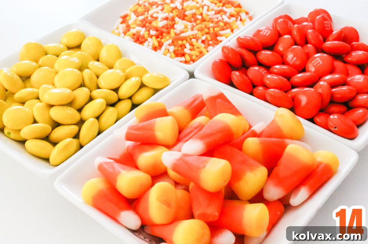 Four ramekins filled with colorful Candy Corn, festive Sprinkles, bright Orange M&M's, and cheerful Yellow M&M's, ready for mixing into the popcorn.