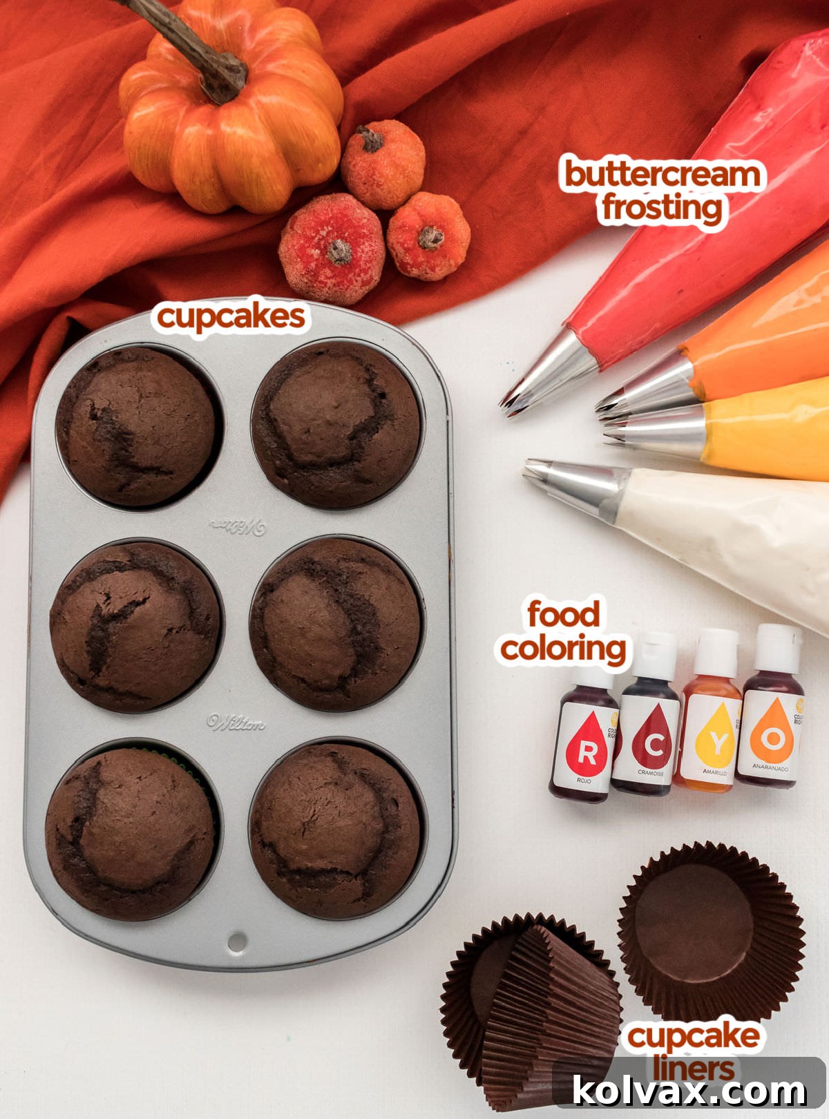All the essential ingredients neatly arranged for making Harvest Thanksgiving Cupcakes, including chocolate cupcakes, a bowl of buttercream frosting, various food colorings, and festive cupcake liners.