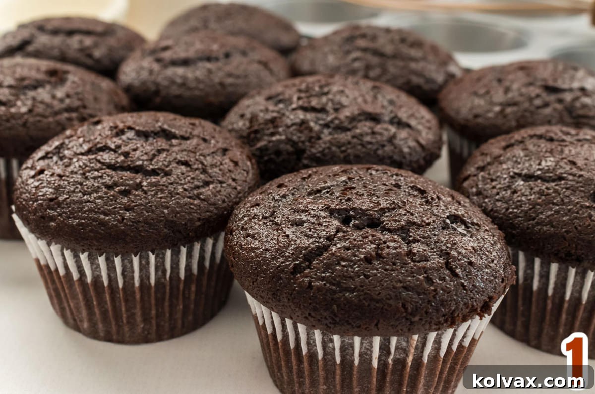 A close-up view of ten perfectly baked chocolate cupcakes arranged on a pristine white table, awaiting their festive frosting.