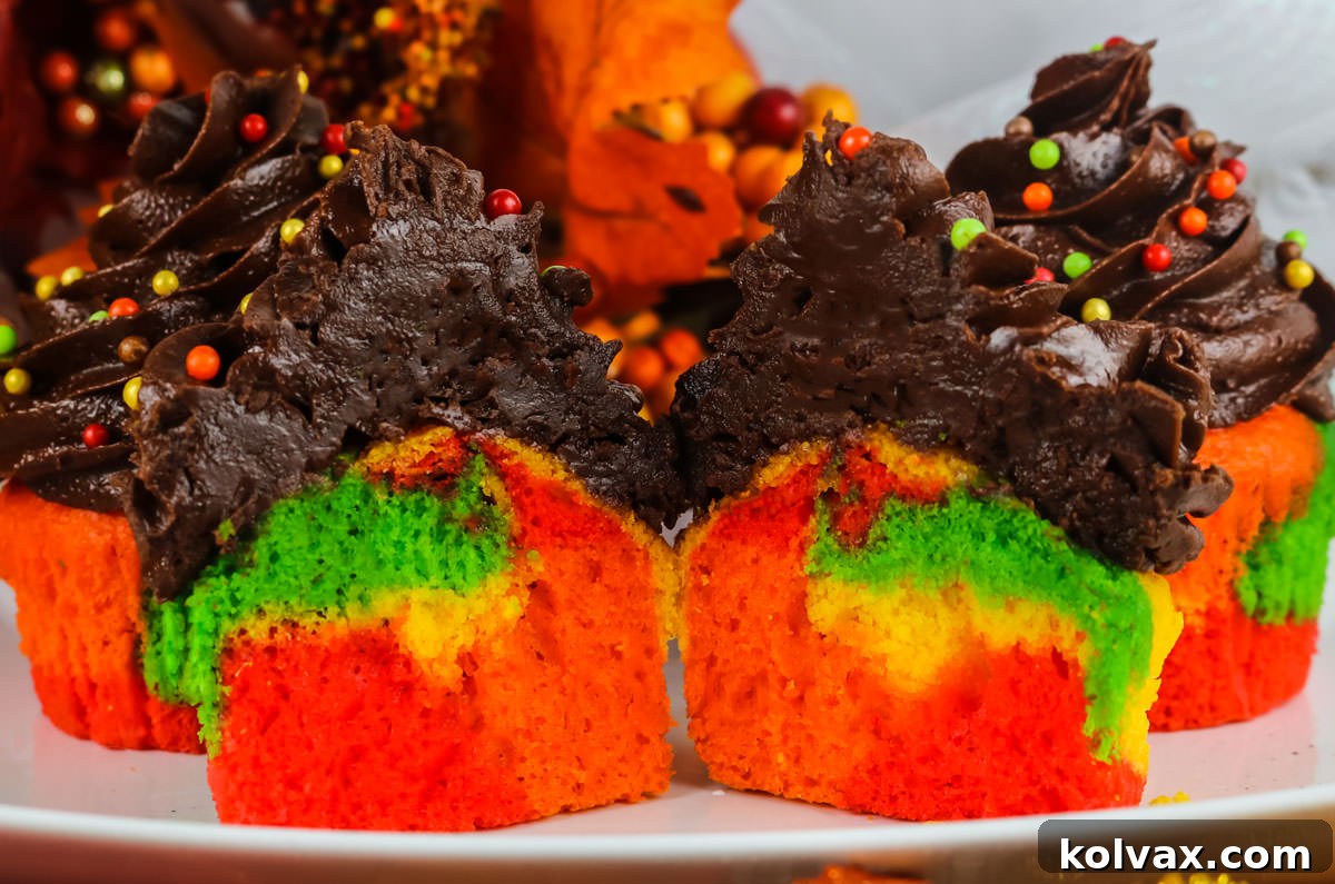 Closeup on four Harvest Marble Cupcakes sitting on a white serving platter, the front cupcake cut in half, revealing the stunning marble interior.