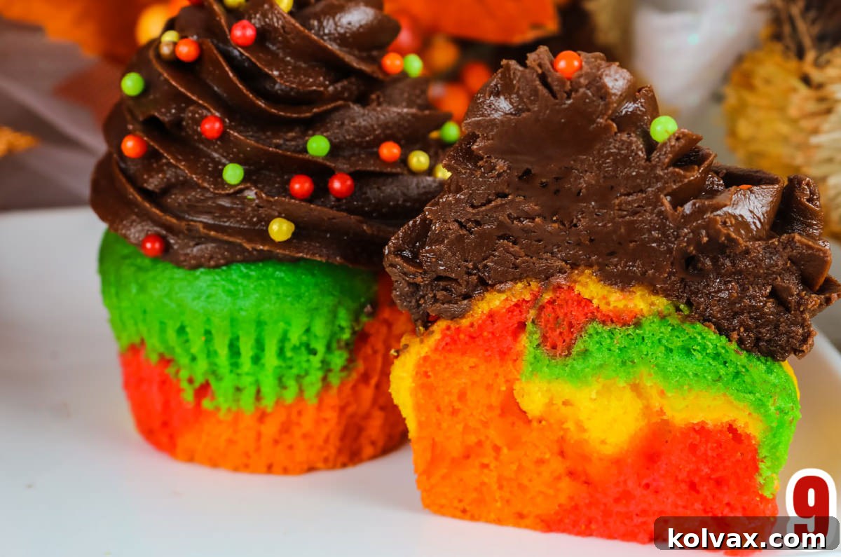 Closeup on two Harvest Marble Cupcakes topped with Chocolate Frosting with one cut in half to show the marble cake inside, highlighting the unique patterns.