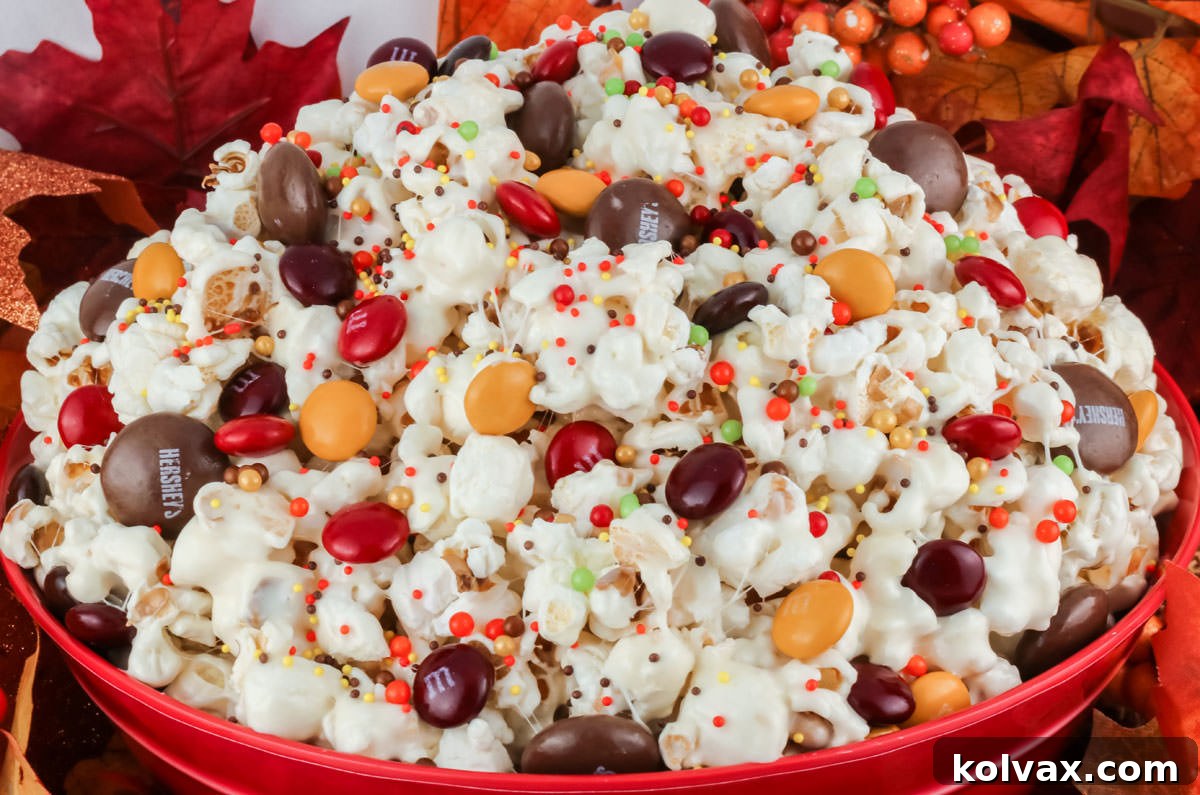 Closeup on a red bowl filled with Fall Harvest Popcorn surrounded by Fall decorations.