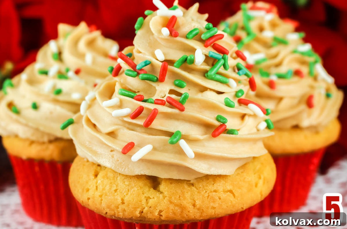 Closeup on the elaborate Butter Rum Frosting swirl applied to an Eggnog Cupcake, topped with festive sprinkles.