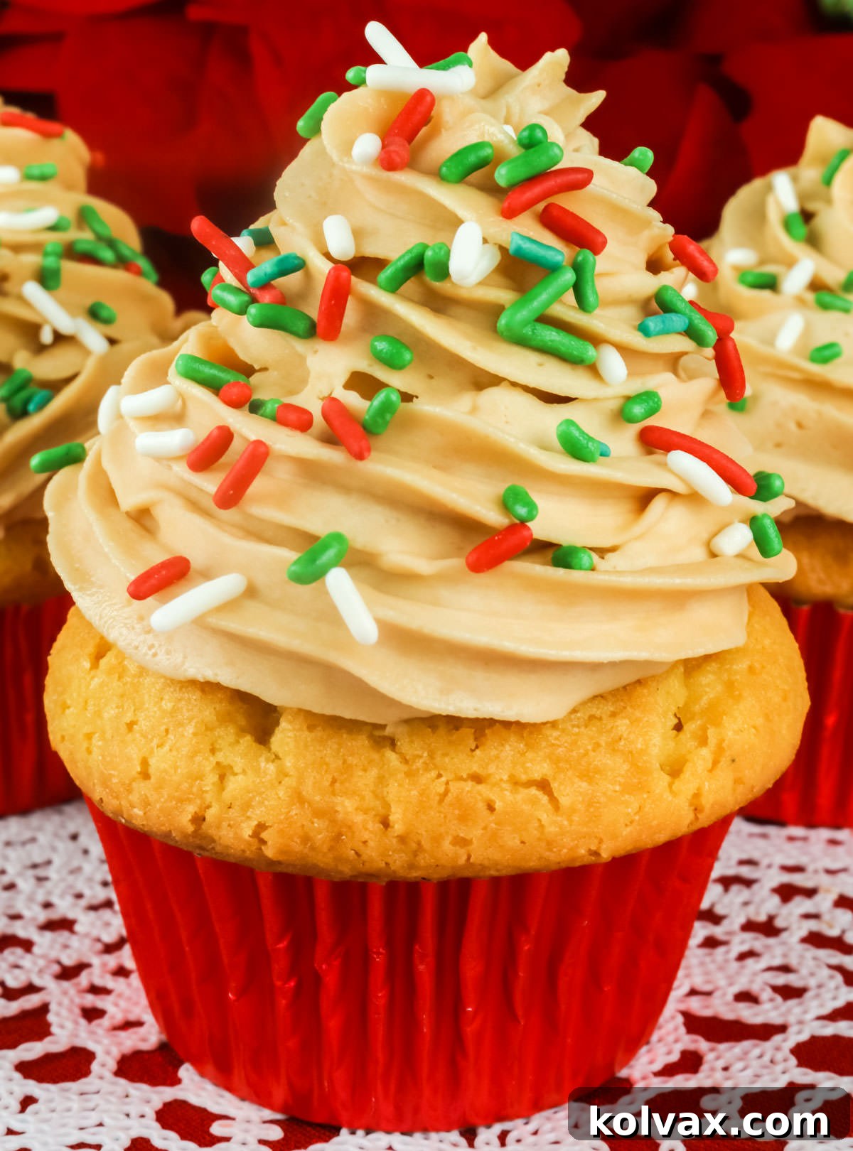 Closeup on a single Eggnog Cupcake with Butter Rum Frosting, showcasing its rich texture and festive sprinkles.