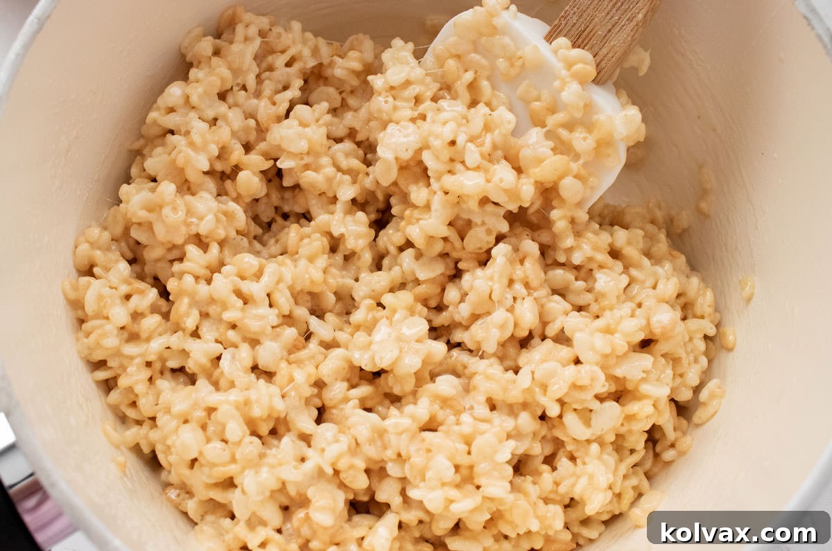Closeup view of a gleaming white pan filled with warm, perfectly mixed Rice Krispie Treat mixture, ready for coloring.