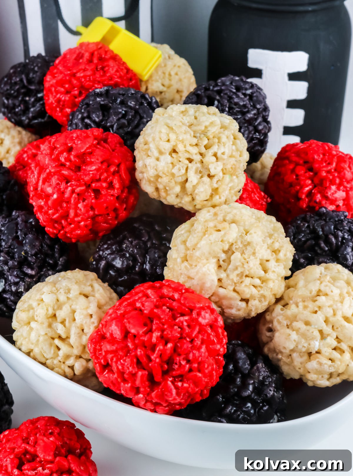 A white serving bowl filled with colorful Atlanta Falcons Rice Krispie Bites, showcasing a trio of red, white, and black treats perfect for sharing.