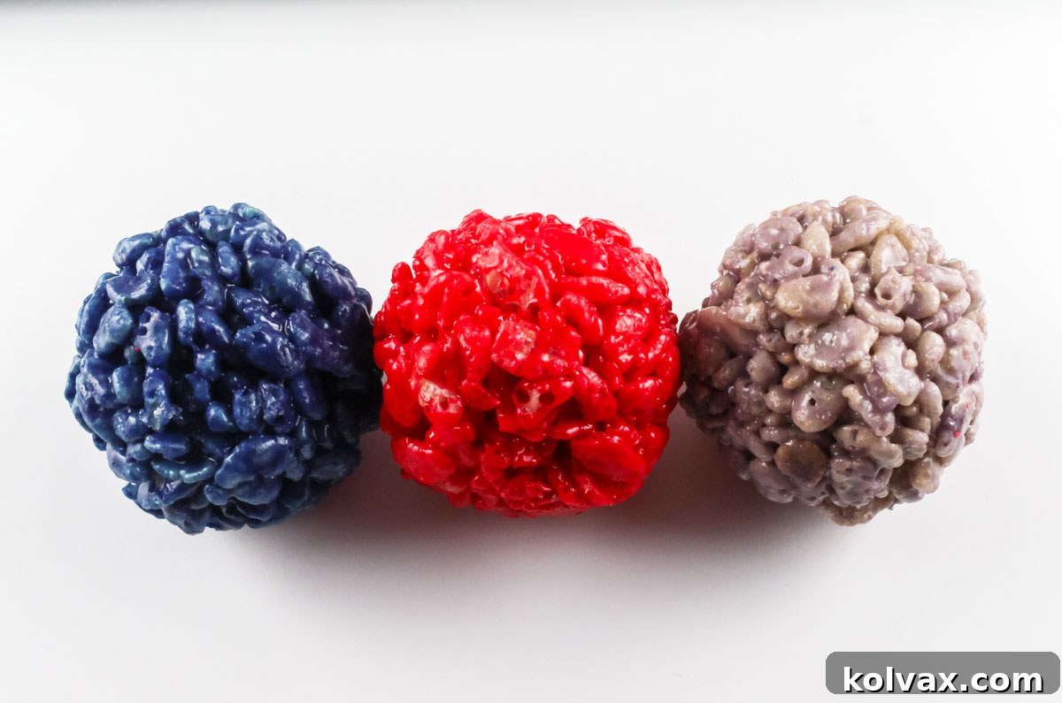 Three perfectly formed New England Patriots Rice Krispie Bites in navy, red, and grey, showcased on a pristine white surface, ready to be enjoyed.