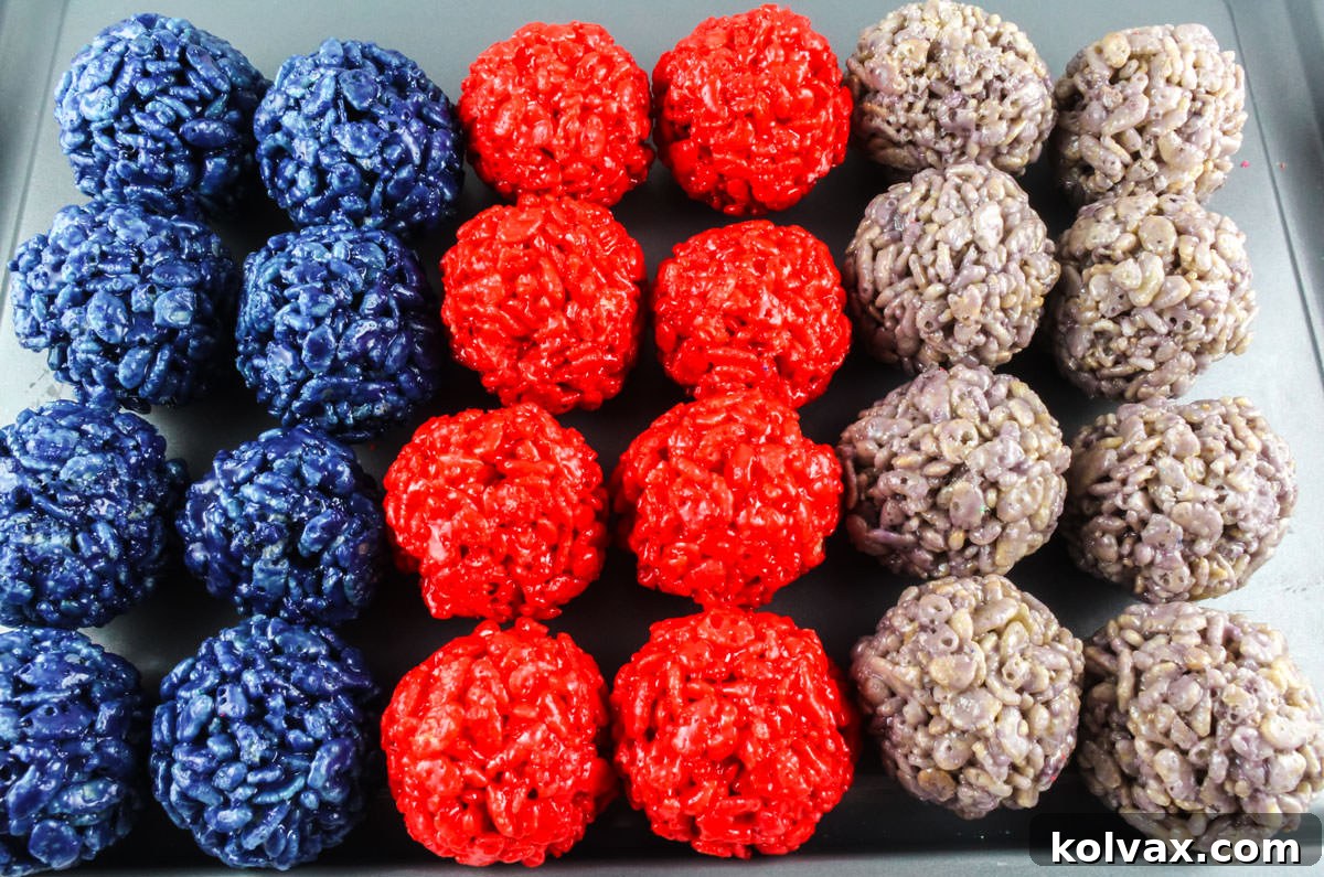 A close-up shot of a baking sheet neatly filled with rows of perfectly formed navy, red, and grey Rice Krispie Bites, showcasing the vibrant team colors ready for a New England Patriots game day party.