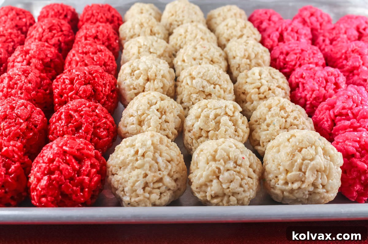 Closeup on a silver cookie sheet filled with rows of Red, White and Pink Rice Krispie Treats Bites.